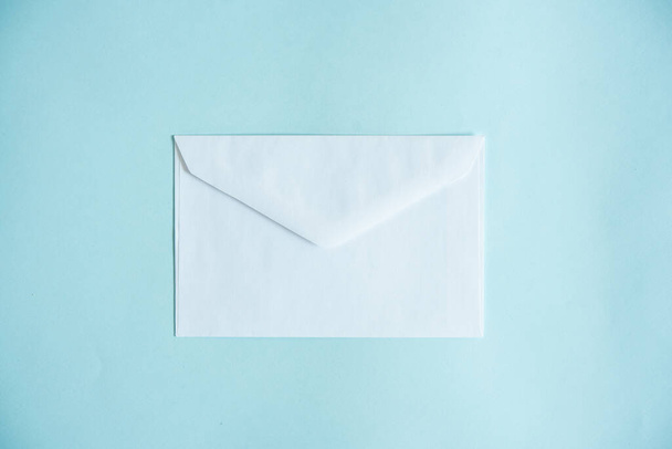een witte envelop op een blauwe achtergrond, stuur een bericht of een nieuwsbericht. - Foto, afbeelding