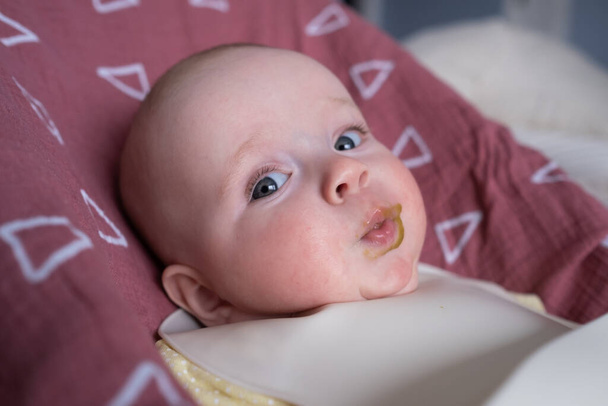 Alimentando um pequeno bebê caucasiano em um babador com uma colher pela primeira vez. - Foto, Imagem