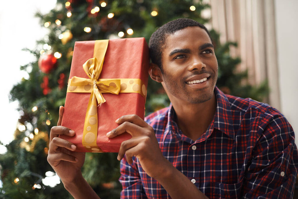 Christmas is my favourite time of year. Shot of a handsome young man getting into the Christmas spirit. - Foto, Imagen