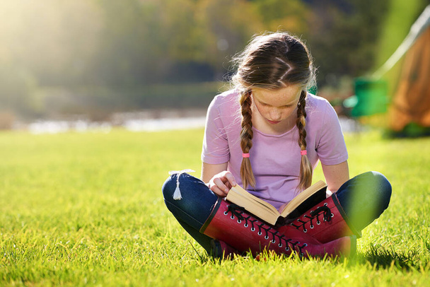 Keep learning all summer long. Shot of a teenage girl relaxing with a book on the grass. - Photo, image