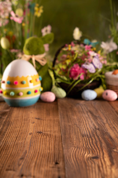 Великодній час. Великодні прикраси на сільському дерев'яному столі. Пасхальний кролик, великодні яйця в кошику. Букети з весняних квітів
.  - Фото, зображення