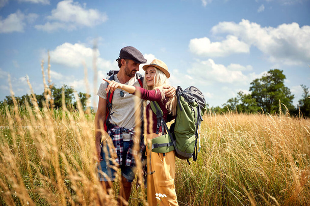 Young couple hiking with backpack in field. Sport, freedom, holiday concept.  - Фото, изображение