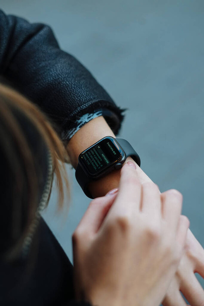 девушка смотрит на часы на руке и нажимает на дисплей - Фото, изображение