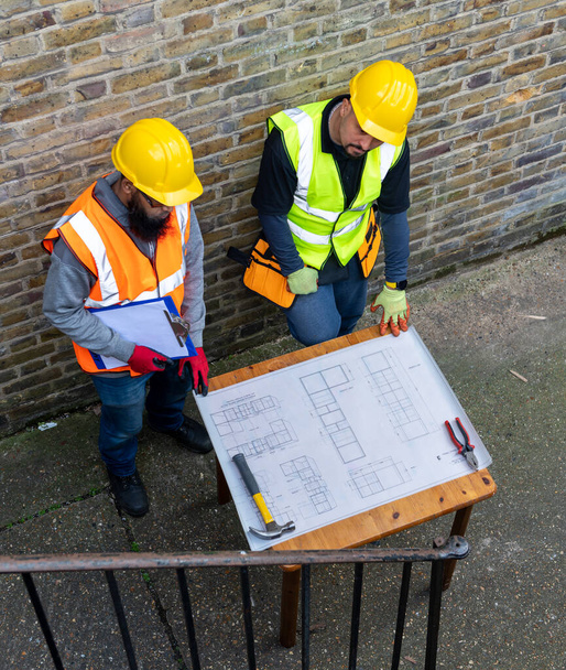 İnşaat işçisi ve amir bina planını inceliyor.. - Fotoğraf, Görsel