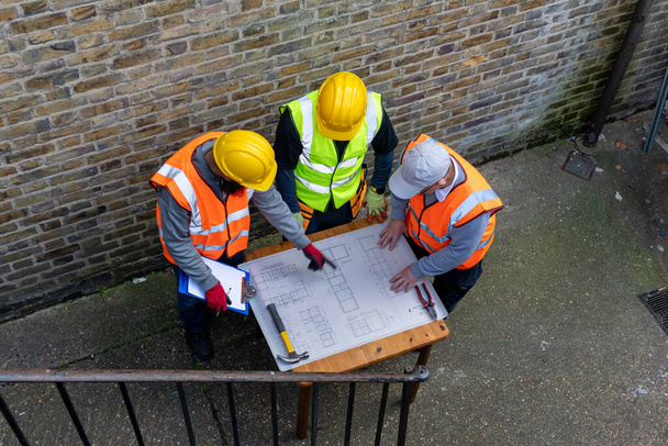 L'architecte avec le plan du bâtiment en discussion avec les superviseurs de la construction. - Photo, image