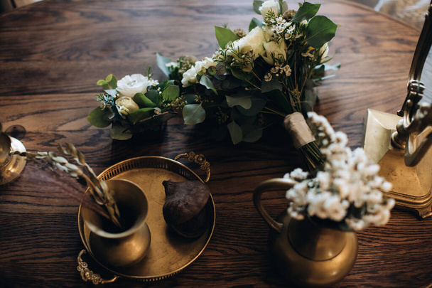 Beautiful wedding bouquets and bronze utensils on a wooden table. Wedding accessories - Zdjęcie, obraz