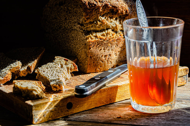 Pão ucraniano caseiro durante a guerra e chá em um copo. Tempos difíceis. - Foto, Imagem