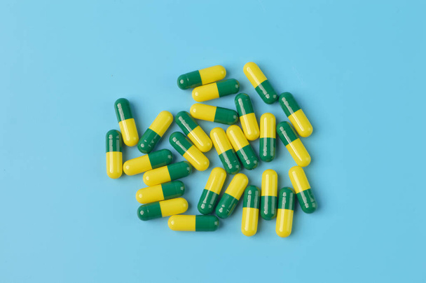 Bunch of pill capsules isolated on a blue background - Foto, afbeelding