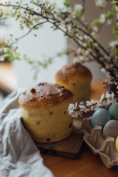 Homemade easter bread, natural dyed eggs and spring blossom on rustic table in room. Happy Easter! Freshly baked easter cake, traditional ukrainian bun - Foto, imagen