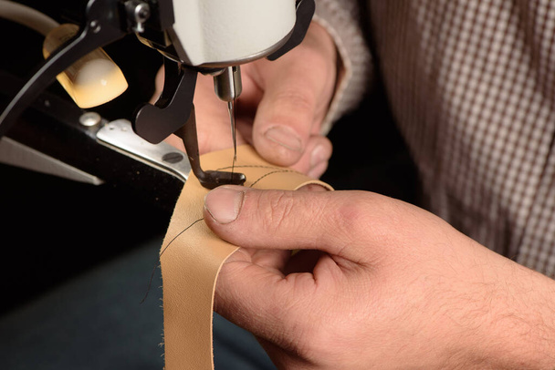 Teollisuuden ompelukone työpajassa suutari. Bootmaker perustaa ammatillinen ompelu laitteet tehtaalla. Lähikuva käsien ompelemalla nahkaa. Valikoiva painopiste - Valokuva, kuva
