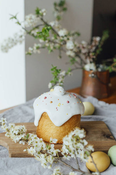 Happy Easter!  Homemade easter bread, natural dyed eggs and spring blossom on rustic table in room. Stylish freshly baked easter cake with sugar glaze and sprinkles, traditional ukrainian bun - Fotografie, Obrázek
