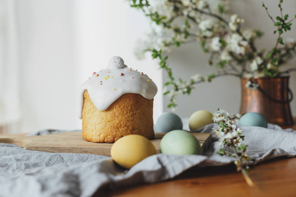 Счастливой Пасхи! Домашний пасхальный хлеб, натуральные окрашенные яйца и весенний цветок на деревенском столе в номере. Стильный свежеиспеченный пасхальный торт с сахарной глазурью и брызгами, традиционная украинская булочка - Фото, изображение