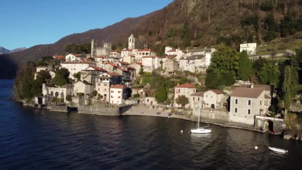 AERIAL VIEW in Verbindung setzen. Kleines Dorf am Comer See neben einem Yachthafen mit festgemachten Booten - Reiseziel - Dervio, Lombardei, Italien - Filmmaterial, Video