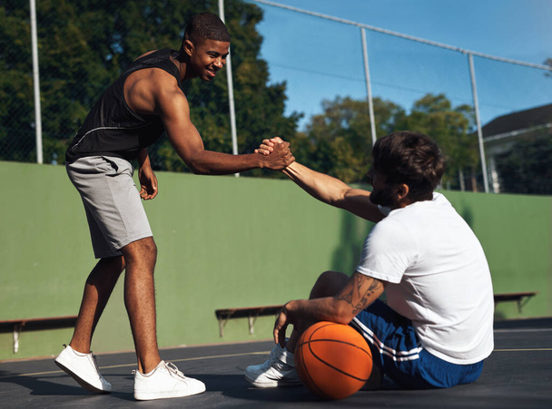 You played so well dude. Shot of two sporty young men shaking hands on a basketball court. - Photo, Image