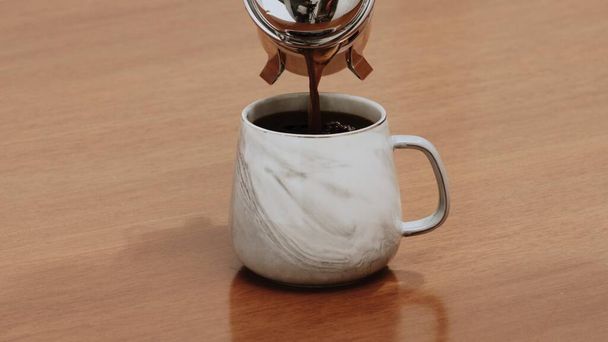 Черный кофе специальности подается в кружке на деревянном столе - Фото, изображение