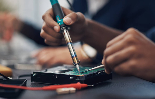 The master at making any computer hardware work. Shot of a technician using a soldering iron .to repair computer hardware. - 写真・画像