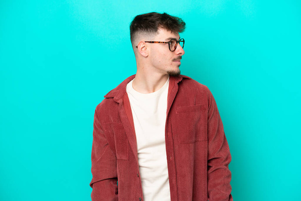 Young caucasian handsome man isolated on blue background looking to the side - Photo, Image