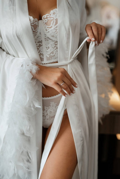 the bride stands with her back in white silk pajamas - Fotó, kép