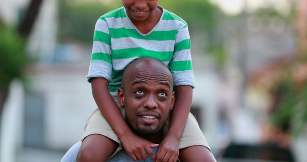 Son on top of father shoulders outside. African black parent and child bonding together outdoors - Foto, Imagem