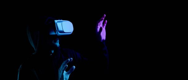 Virtual reality game vr. Young man in digital glasses for virtual reality technology isolated on dark neon background. Study and virtual world in 3D simulation. - Photo, Image