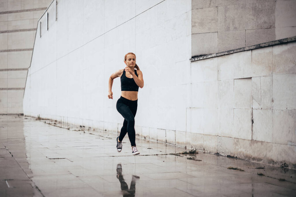 Mladá žena běhá po městě. Běh fitness dívka ve sportovním oblečení venku. - Fotografie, Obrázek