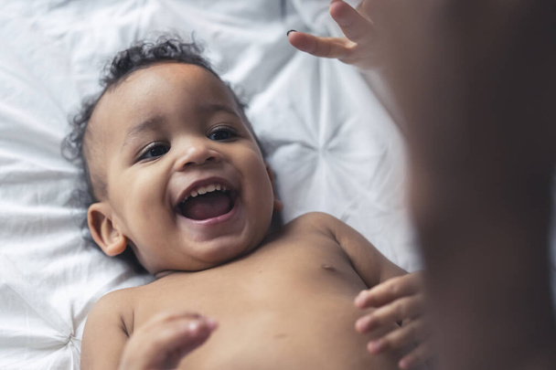 Entzückendes Baby mit gemischter Rasse legt sich hin und lächelt. Glückliche Kindheit. - Foto, Bild