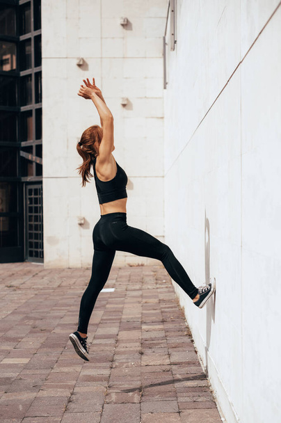 都市部の壁からバックフリップを行う若いパルクールとフリーランニングの女性,タンブル体操のトレーニングコンセプトをジャンプ - 写真・画像