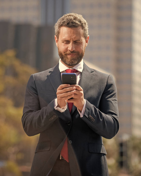 スーツ姿のビジネスマンが屋外に立って電話でチャット - 写真・画像