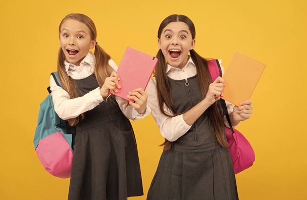 Happy children in formal school uniforms hold study books yellow background, knowledge day - Photo, Image