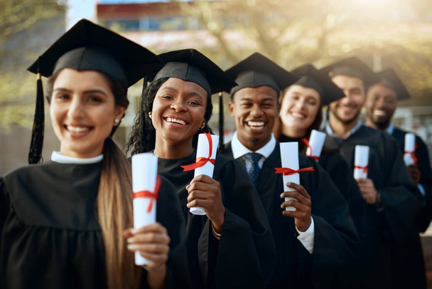 Our future is secure. Portrait of a group of young students holding their diplomas on graduation day. - Фото, изображение