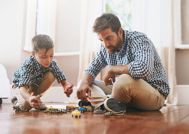 Dad makes time for play in his busy day. Shot of a young boy and his father playing with cars on the floor. - Zdjęcie, obraz