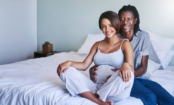 Hes been a real help through my pregnancy. Shot of a young expecting couple sitting on their bed. - Fotó, kép