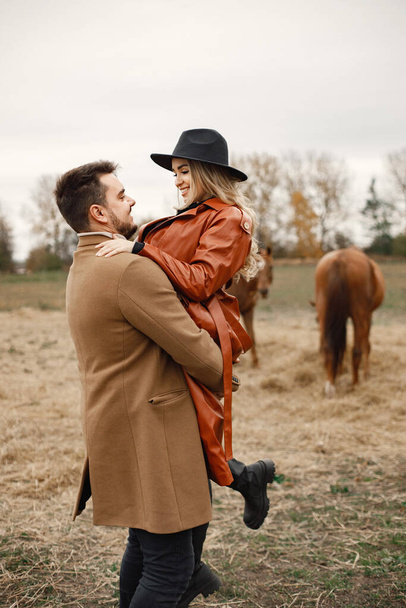 Romantisch koppel wandelen in het veld met paarden - Foto, afbeelding