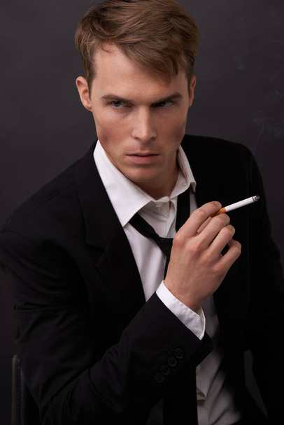 Przekazuję Jamesa Bonda. Przystojny młody mężczyzna w garniturze z papierosem w ręku. - Zdjęcie, obraz