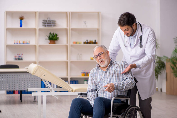 Vanha mies pyörätuolissa vierailulla nuori mies lääkäri - Valokuva, kuva