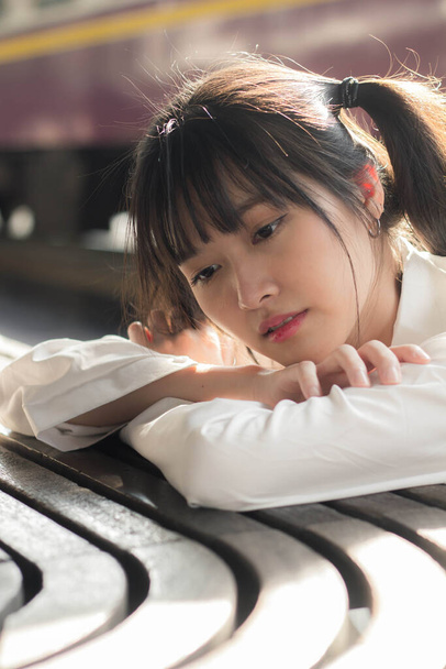 Portré thai japán felnőtt gyönyörű lány fehér ing kék farmer pihenési idő, vasútállomás divat - Fotó, kép