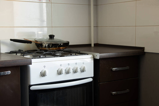 Gasfornuis en vuile koekenpan in de keuken in een appartement in Oekraïne, keukenmeubels en -apparatuur, keukeninterieur - Foto, afbeelding
