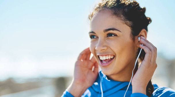 Esta lista de reproducción es conmovedora. Fotografía de una joven deportista escuchando música mientras hace ejercicio al aire libre. - Foto, Imagen