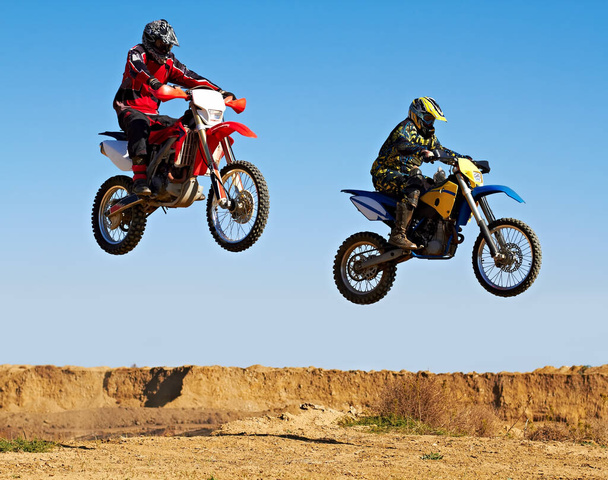 Saltando al unísono. Acción de tiro de dos motociclistas de tierra en el aire. - Foto, Imagen