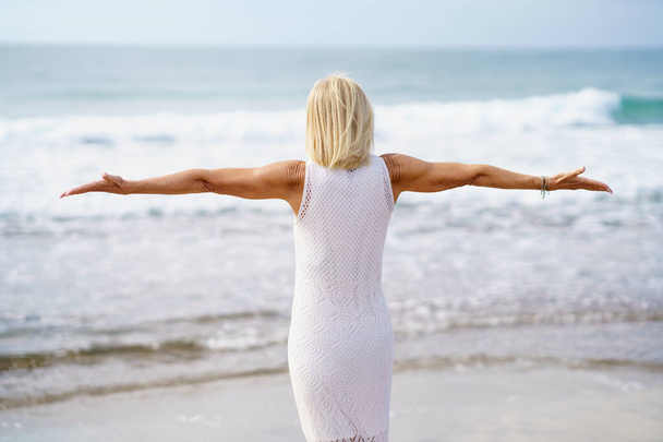 Mulher madura anônima com braços estendidos na praia - Foto, Imagem