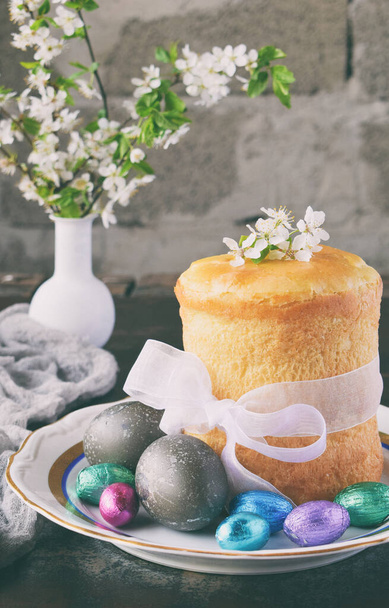 Mutlu Paskalya kavramı. Tatlı ekmek yemiş/kuru meyveler ve renkli yumurta ile. Tatil kahvaltı. Ortodoks kulich. Festival tablo yer dekorasyon paska, çiçeği twigs, bunny, çikolata yumurta ile. - Fotoğraf, Görsel