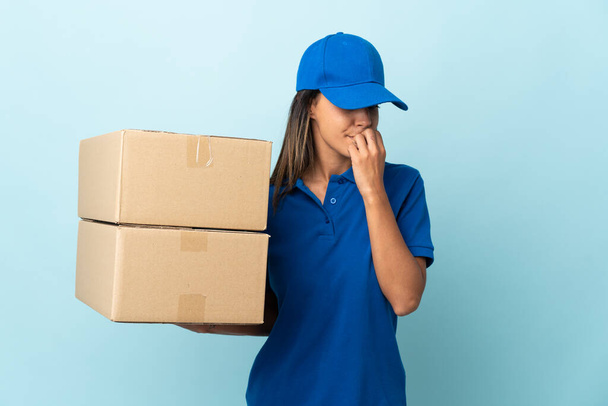 Young delivery woman isolated on blue background having doubts - Photo, Image