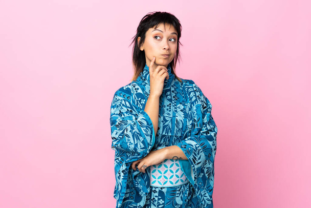 Young woman wearing kimono over isolated blue background and thinking - Fotografie, Obrázek