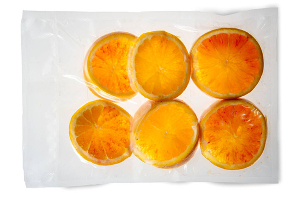 Süpürgedeki portakal dilimleri beyaz arka planda izole edilmiş soous vide pişirme için paketlenmiş. - Fotoğraf, Görsel