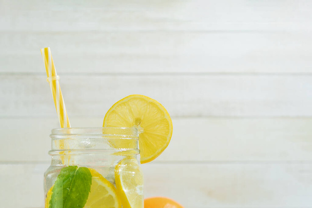 Свіжий цитрусовий лимонад з м'ятою на сільському тлі. Лимонад та інгредієнти на фоні дерева, копіюють простір. Літній лимонад з лаймом і м'ятою на жовтому сонячному фоні
 - Фото, зображення