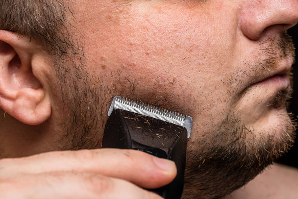 Mężczyzna golenie lub przycinanie brody za pomocą strzyżenia włosów - Zdjęcie, obraz