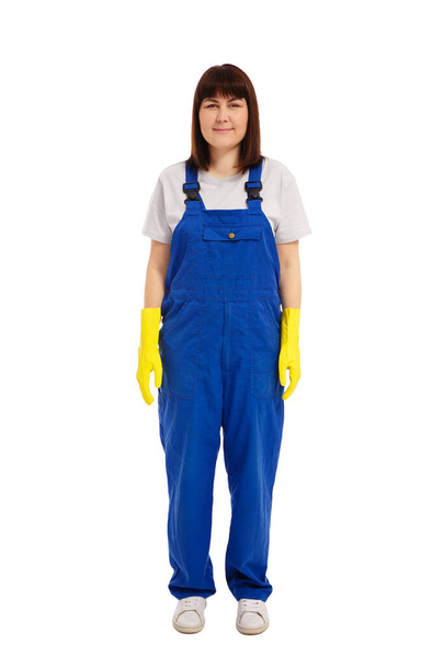 retrato de cuerpo entero de limpiadora joven en uniforme azul y guantes amarillos aislados sobre fondo blanco - Foto, Imagen