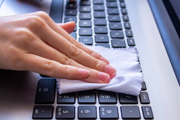 Laptop klavyesini beyaz bir bezle temizleyen kadın.. - Fotoğraf, Görsel