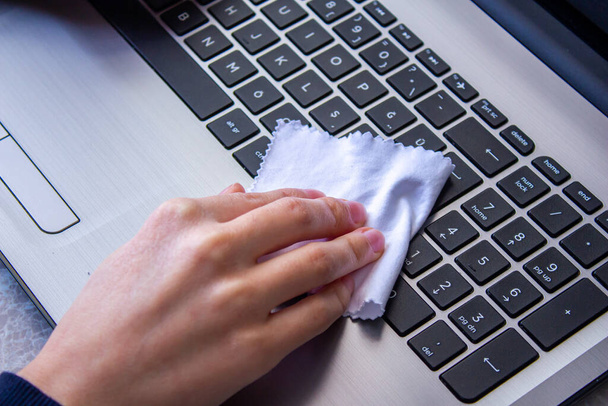 Женщина чистит клавиатуру ноутбука белой тканью. - Фото, изображение