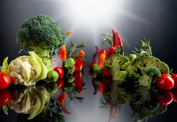黒反射を背景に様々な生野菜。菜食主義をテーマにしたコンセプチュアルなイメージ.  - 写真・画像